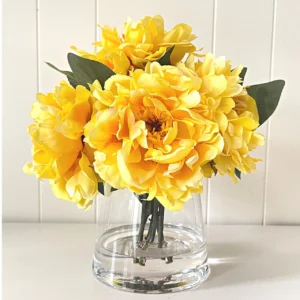 A picture of yellow peonies in a glass container.