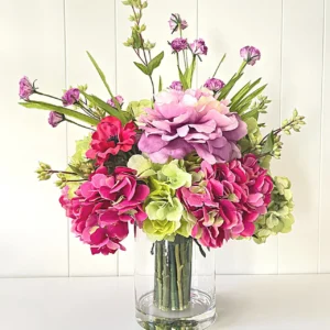 A picture of mixed artificial flowers in a glass vase.