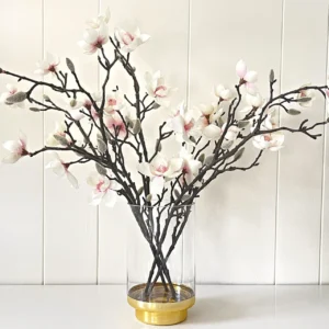 A picture of magnolia blooms in an old-rimmed glass container.